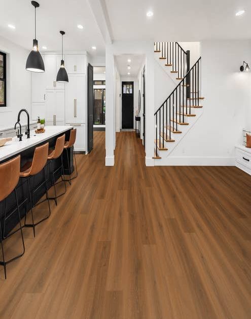 Modern-style staircase, entryway, and black-and-white kitchen island with leather chairs pulled up and medium toned lamiante floors