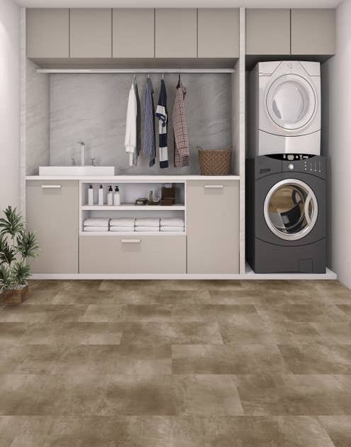 Laundry room with built-in light gray cabinets, stacked white/gray washer and dryer, and hanging shirts with gray and tan concrete-look LVT