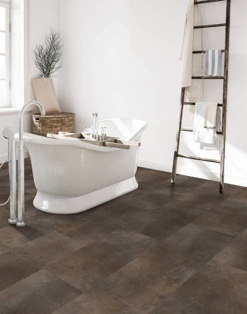 Modern white bathroom with a white free-standing bathtub, a rustic ladder shelf with towels, and a brown tile-look LVT floor