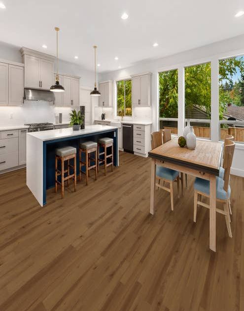 White and blue kitchen and dining room table and chairs over golden brown vinyl plank floors, with large windows overlooking outdoor deck