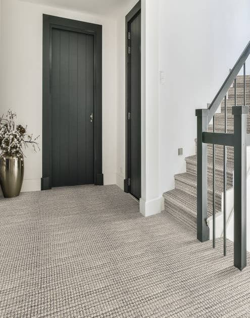 Avalon Denim carpet in shades of blue and cream at the bottom of a staircase, on the stairs in a hallway