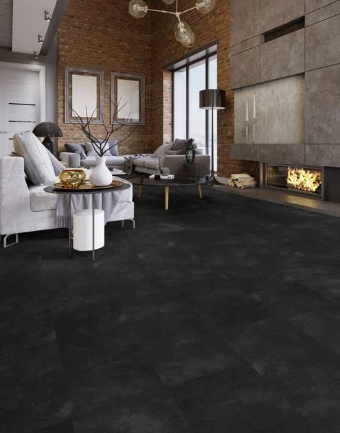 Industrial-inspired living room with exposed brick walls, large modern concrete fireplace, couches, and black and charcoal stone-look tiles