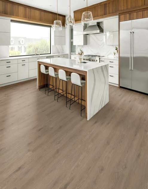 Modern organic wood and white kitchen with marble island, chairs, large window, refrigerator, over gray-brown wide-plank floor