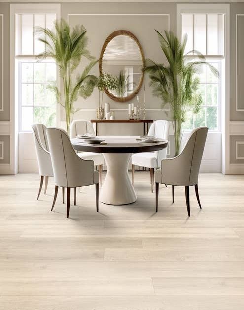 Bright and airy dining room with large windows flanking palm fronds, a large gold mirror, and a table surrounded by four modern chairs