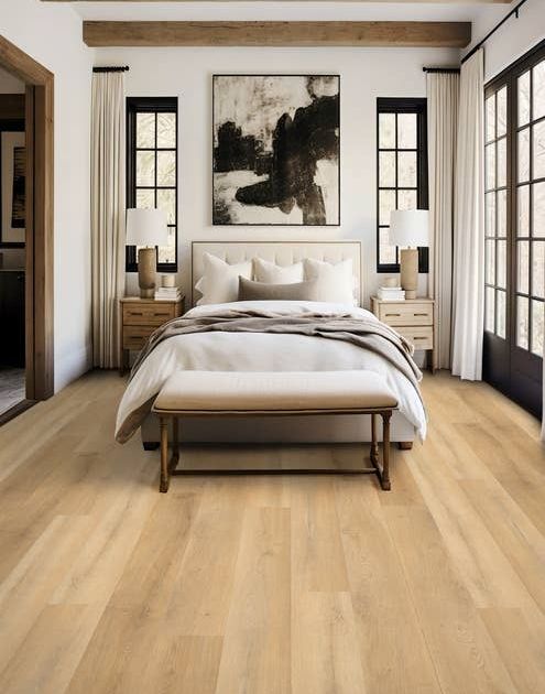 Inviting bedroom with white walls, pale tan woodgrain floors, wooden beams, black-framed windows, modern art, and an organic-inspired bedroom set