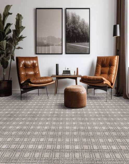 Modern home seating area with two brown leather chairs and an ottoman on a gray plaid geometric carpet