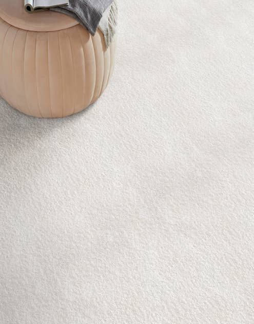 Modern tan ottoman on solid white textured carpet