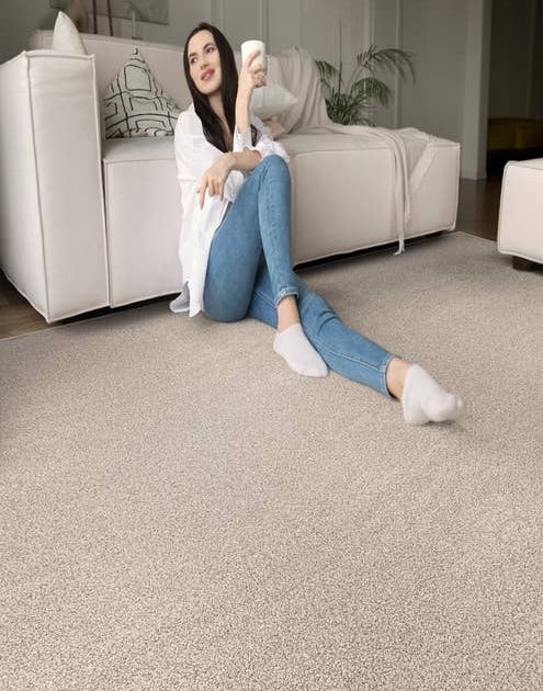 Woman leaning against white sofa on cream solid textured carpet