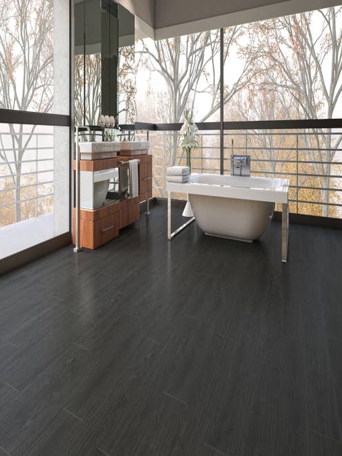 Luxury spa space and vanity set on black woodgrain LVP floor, surrounded by floor-to-ceiling windows featuring autumnal woods beyond