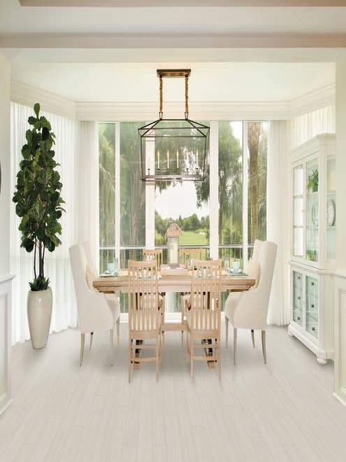Bright, airy dining room with large window, chandelier, table, china cabinet, and potted tree over white Blank Canvas floor