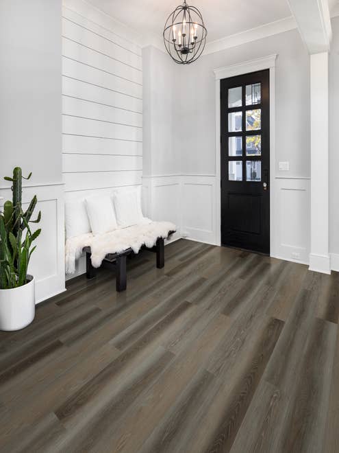 Modern farmhouse entryway with crisp white shiplap accent wall, dark variegated woodgrain floor, and chandelier