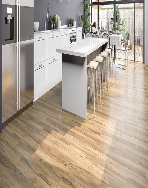 White kitchen cabinets and light gray and taupe LVP floor, with bar stools at island, with small table, and glass doors leading to deck