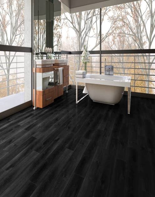 Spa space with large wooden vanity and tub facing wall of windows that show autumnal foliage outside