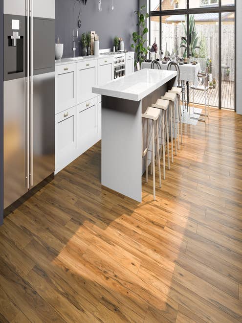White kitchen cabinets and golden brown LVP floor, with bar stools at island, with small table, and glass doors leading to deck