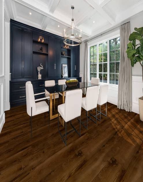 Moody dining area featuring navy built-ins, rich dark floor, large windows, and silver chandelier