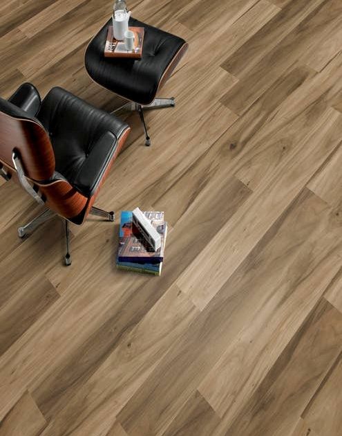 Modern leather office chair and matching ottoman beside stack of books, over Hickory Lake Teak laminate floor