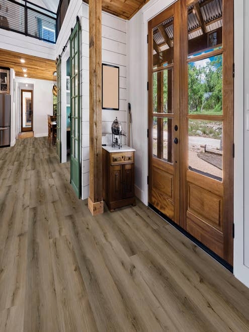 Wooden entry door and hall, with white shiplap walls and lightly-weathered wide plank brown Ash Brown floor