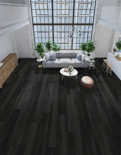 Dark, dramatic Oakdale Onyx floor in bright urban apartment with towering windows, couch, coffee table, credenza, houseplants, and kitchen island