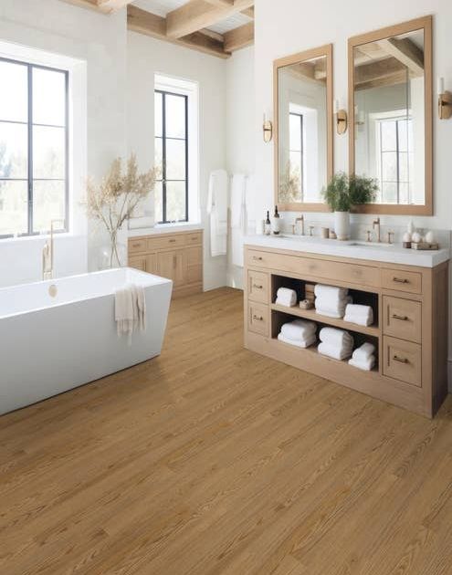 Luxurious bathroom with white walls, exposed wood beams, natural light, free-standing tub, and dual sink organic wooden vanity, over Oakridge Barley LVP