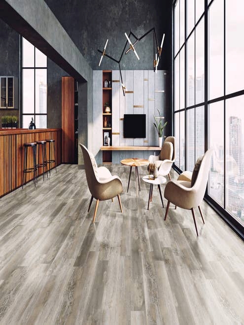Urban studio apartment seating area beside kitchen barstools, facing large windows overlooking city, with black concrete walls and distressed gray wood look LVP