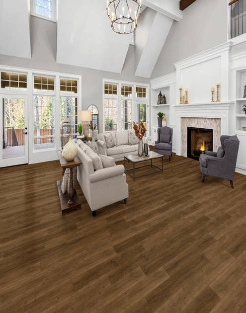 Contemporary living room with vaulted ceilings, gray walls, medium brown wood-look floor, built-in shelving, a wall of large windows, and couches and chairs before a fireplace
