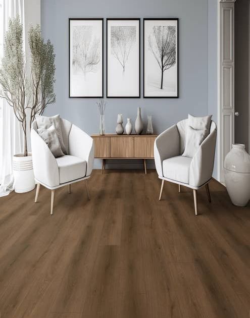 Two white armchairs, wooden credenza, and large potted tree before three paintings, in room with pale blue walls and medium brown LVP floor