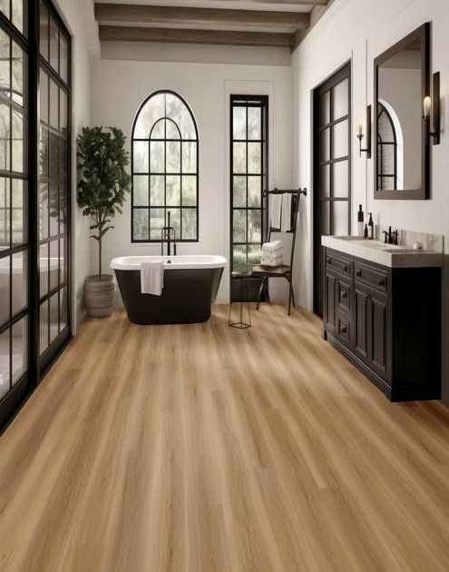 Black, white, and natural wood tone bathroom with black-framed windows, tub, vanity, mirror, and exposed wooden beam, with light brown wood-look LVP flooring