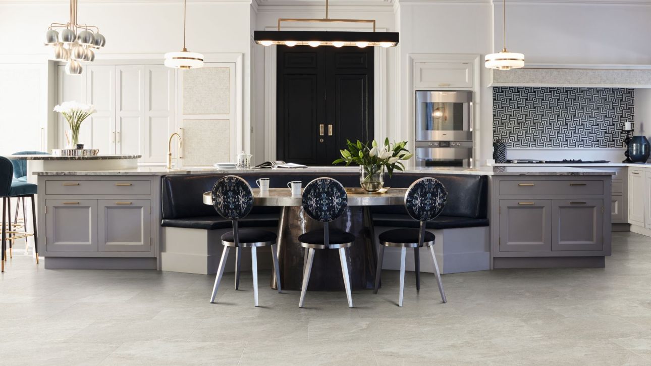 Kitchen with built-in cabinets, large black door, oversized island, multiple light fixtures, and built-in breakfast bench with table and chairs