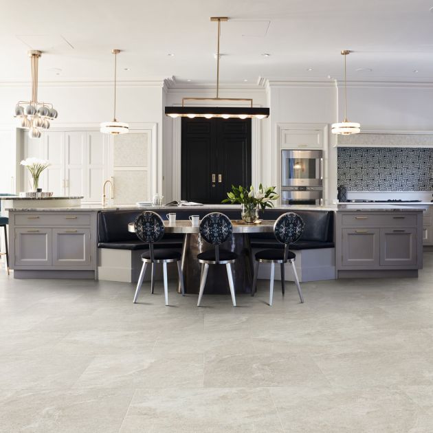 Kitchen with built-in cabinets, large black door, oversized island, multiple light fixtures, and built-in breakfast bench with table and chairs