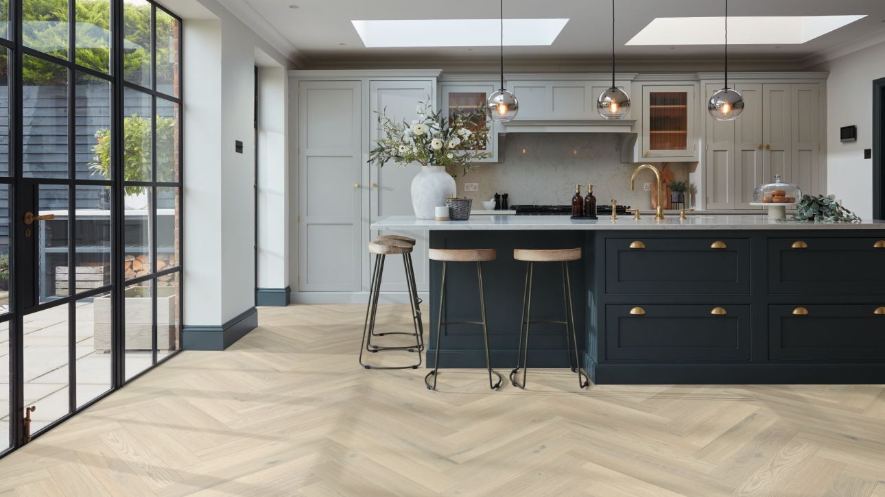 Kitchen with large bright windows, sky lights, pendant lights, built-in cabinets, and blue island with barstools over taupe/beige herringbone woodgrain floor
