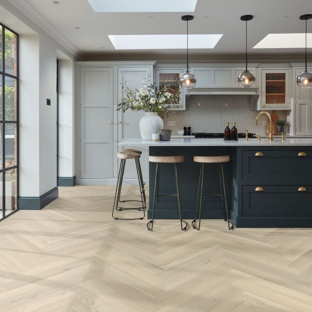 Kitchen with large bright windows, sky lights, pendant lights, built-in cabinets, and blue island with barstools over taupe/beige herringbone woodgrain floor