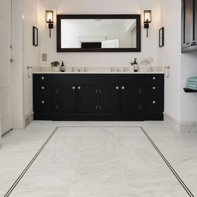 Bathroom with black dual sink vanity, black sconces, and large black-rimmed mirror, with white marble-look LV floors and an inlaid black design border