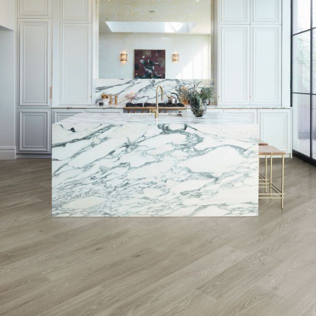 Bright airy kitchen with black-framed windows, white cabinets, marble island, with gold metal barstools, gold fixtures, and a diagonal grey woodgrain floor
