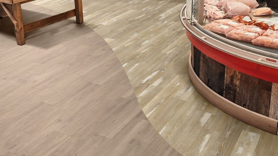 Retail grocery space featuring distressed blond oak and cool brown wood flooring, with table piled with jarred preserves and glass display case filled with various meats