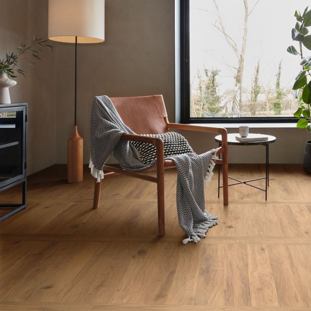 Mid-century chair and floor lamp before large window, with golden brown floor installed with perpendicular planks for a grid effect