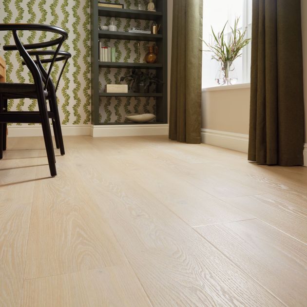 Dining room floor, a pale taupe wood-look floor with black chairs and bookshelf in background, with houseplant on windowsill surrounded by drapes
