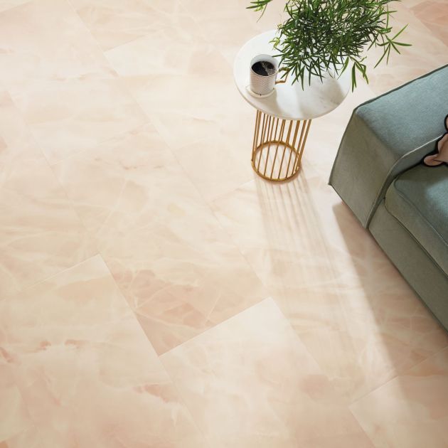 Overhead shot with sofa arm, side table, plant, and coffee cup, over pink stone-inspired tile floor