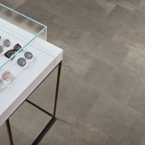 Retail space featuring various sunglasses in display table with rectangular gray tile floor