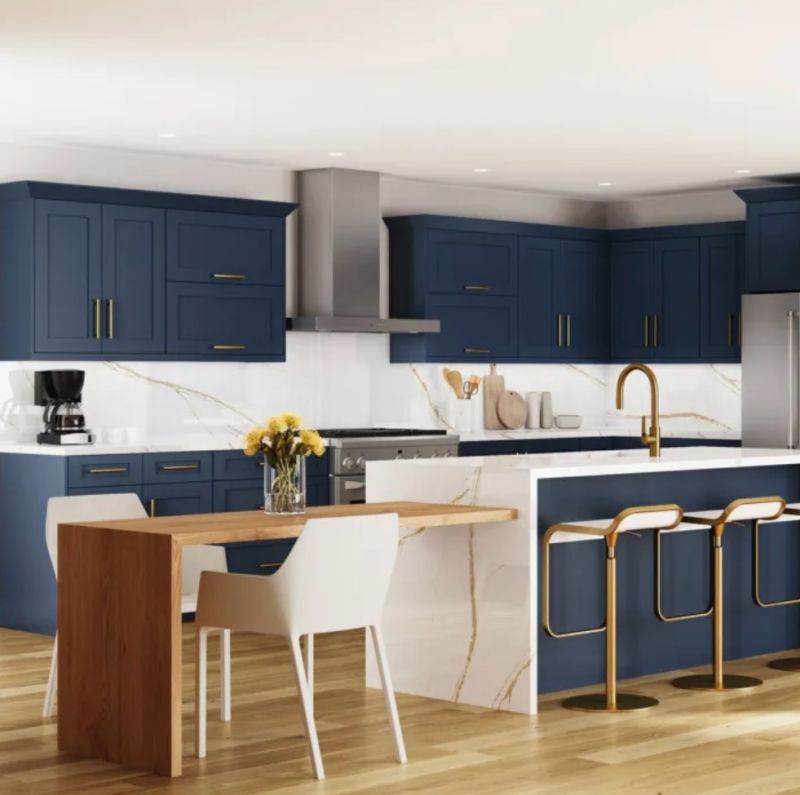 Blue kitchen cabinetry and island with white marble counters, bar stools, and small modern wooden table with chairs