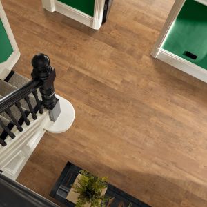 Photo overlooking black staircase and hallway with brow woodgrain LVP floor, in space with green walls