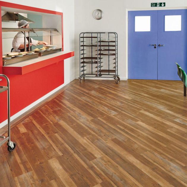 Cafeteria space with red food window, green chairs, blue doors, and medium brown weathered planks installed at an angle