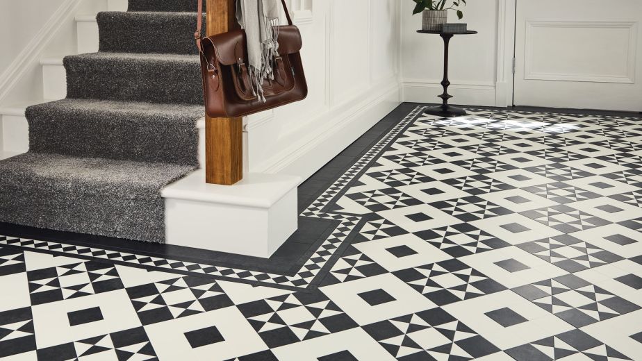 Entry hall with carpeted staircase, hanging purse and scarf, and black and white Victorian tile flooring