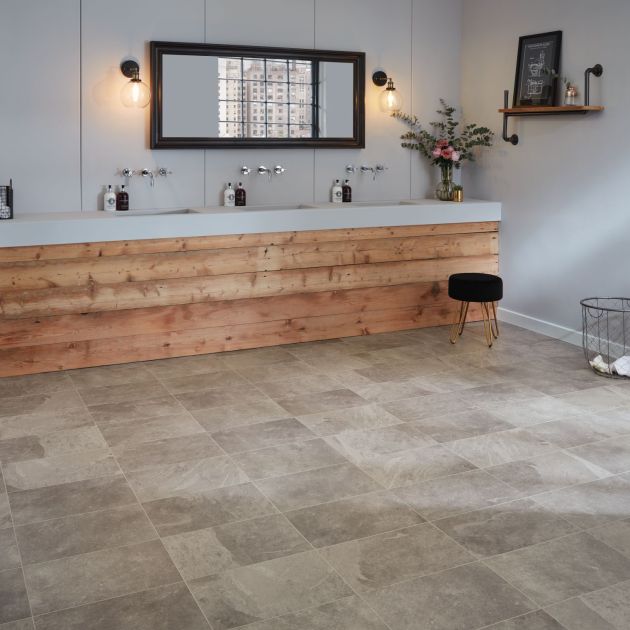 Industrial-style bathroom with multiple sinks in wood vanity, sconces, shelf, and stool on gray rectangular tile floor