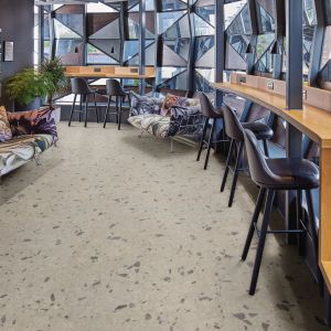 Modern office space with geometric glass wall flanked by an arc of desks, stools, and patterned couches