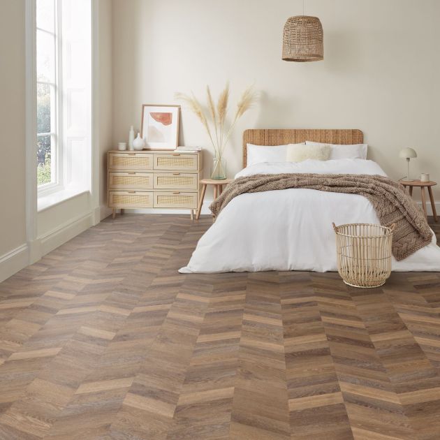Bedroom with natural light and pale brown chevron woodgrain flooring, with bed, nightstand, and various organic elements