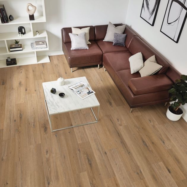 Living space with leather sofa, bookshelf, and coffee table over warm brown woodgrain floor