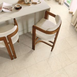 Marble kitchen island topped with coffee and book, with two bar chairs over cream LV floor