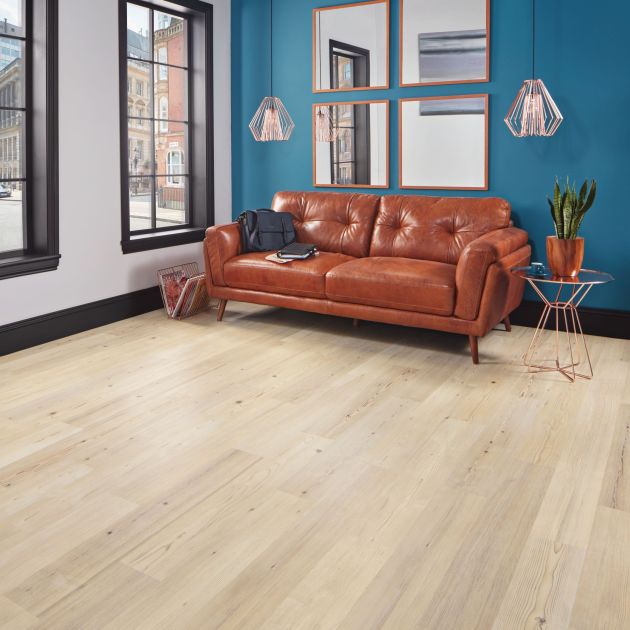 Living space with bright blue feature wall, leather sofa, side table, hanging mirrors, large windows, and light woodgrain LVP floor