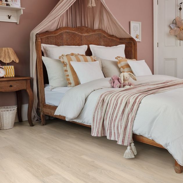 Girl's bedroom with canopy bed, stuffed animals, nightstand, and hanging shelves, with pale woodgrain LVP floors