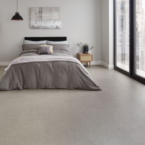 Monochrome bedroom featuring gray concrete-look floor, small nightstand, artwork, pendant light, and glass sliding door to balcony